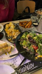 Dinner table at a Chania restaurant with salads, fries, pita and grilled dishes