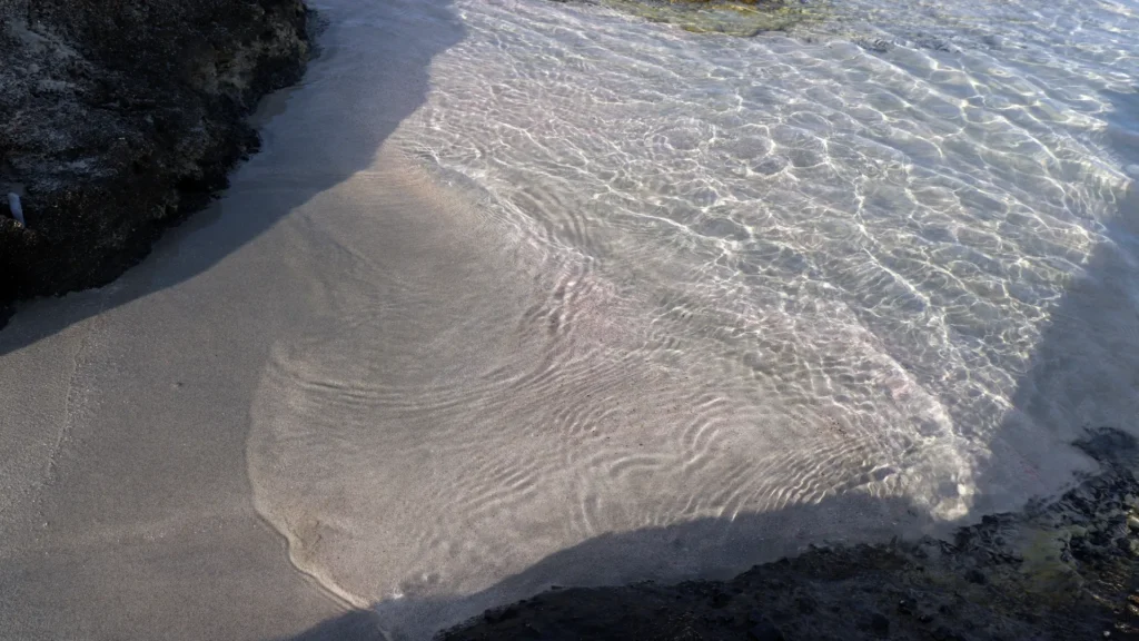Pink sand blending with crystal-clear shallow water at Elafonissi Beach Crete — photo by Zurab Pekirishvili, Canon 800D