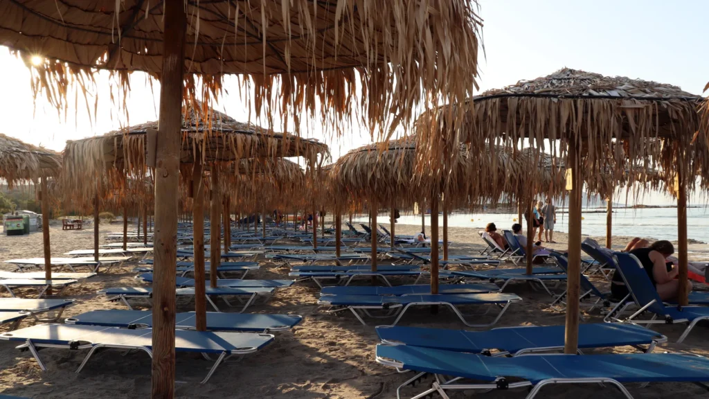 Sunbeds and straw umbrellas on Elafonissi Beach at sunrise — photo by Zurab Pekirishvili