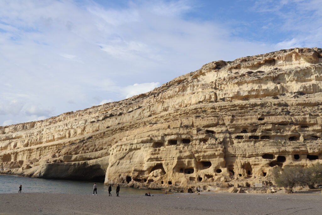 Matala caves on the cliff during winter with a quiet sandy beach in Crete