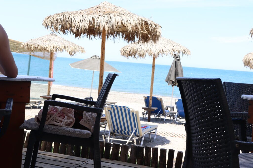 Straw umbrellas and sunbeds on Ayia Marina Beach with a calm sea view