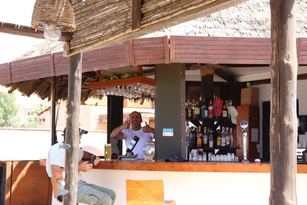 Beach bar counter with tropical decor and a friendly staff member in Ayia Marina