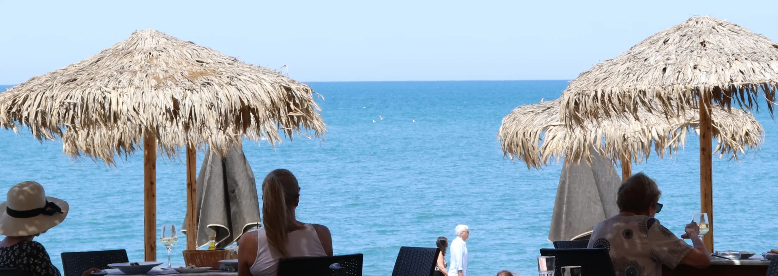 Straw umbrellas and beachgoers relaxing by the turquoise sea in Ayia Marina