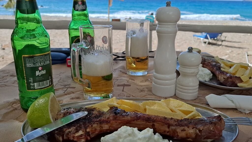 Pork brizola with fries, tzatziki and Mythos beer at Sunset Fish Restaurant in Sfinari