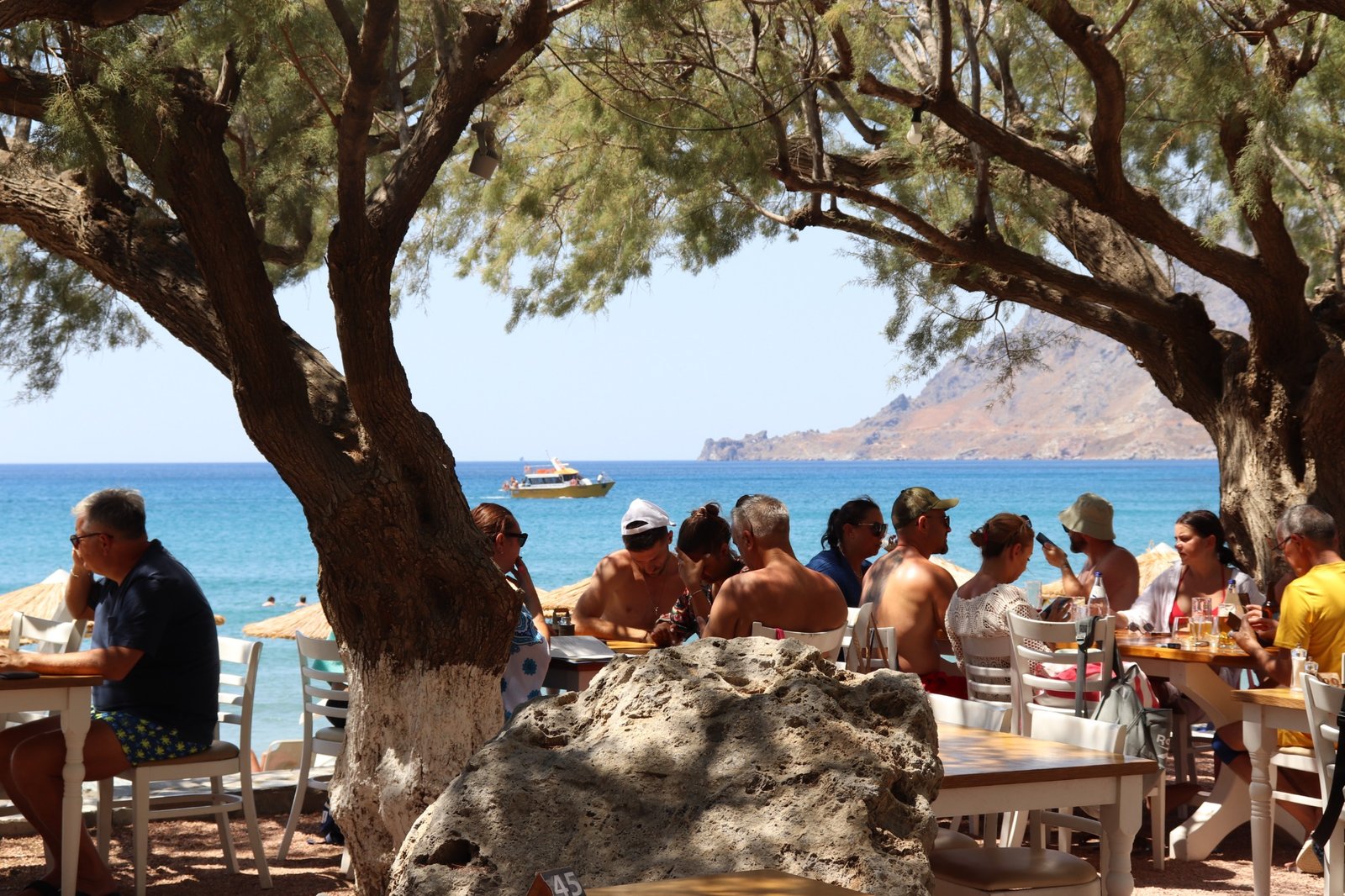 Shaded Seafront Seating at Alianthos Seaside Restaurant, Plakias Guests sitting under tamarisk trees at Alianthos Seaside Restaurant in Plakias, Crete