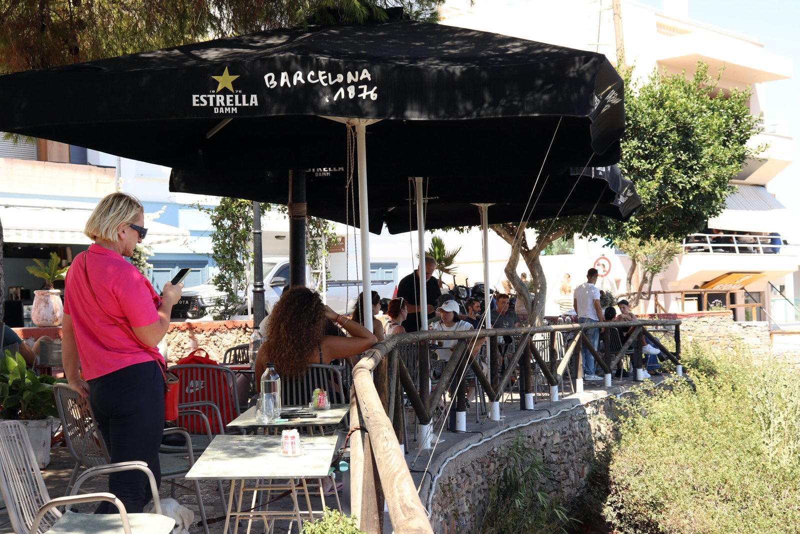 ARC Café Shaded Terrace — Agios Nikolaos ARC Café shaded terrace in Agios Nikolaos with summer visitors and Estrella umbrellas overlooking the lake