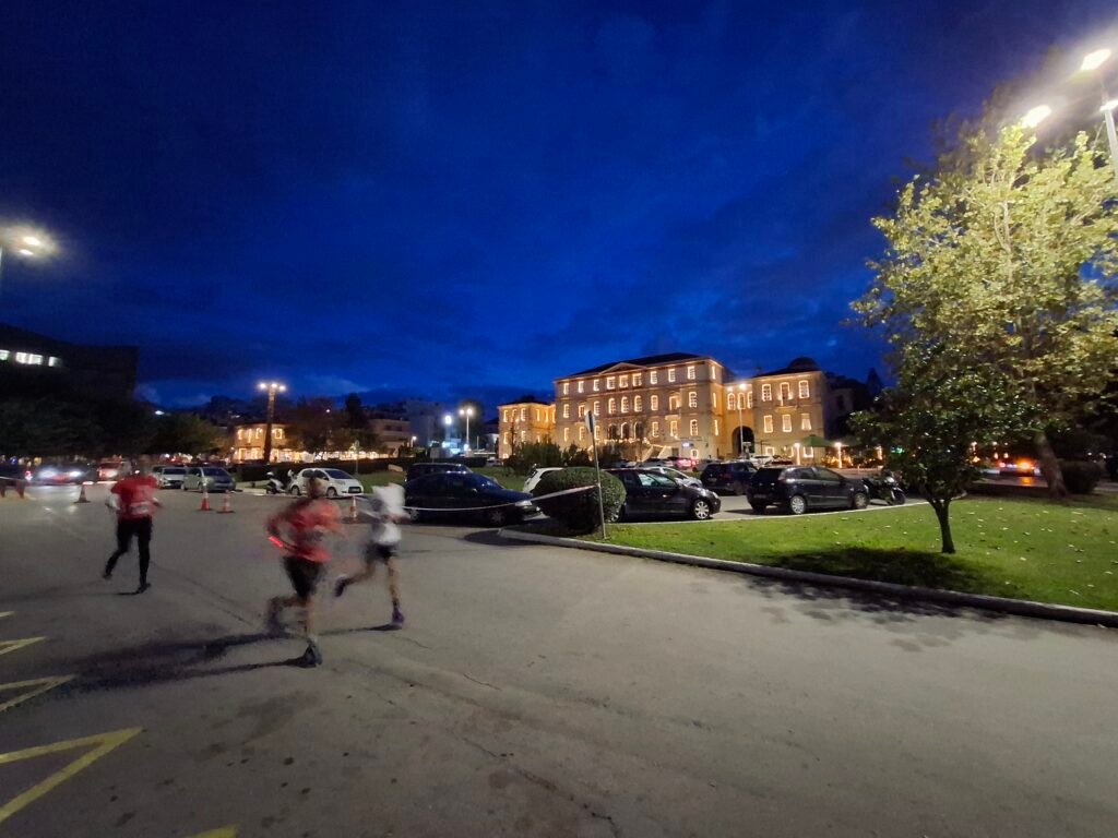 Night runners passing illuminated buildings during the Chania Night Run 2025