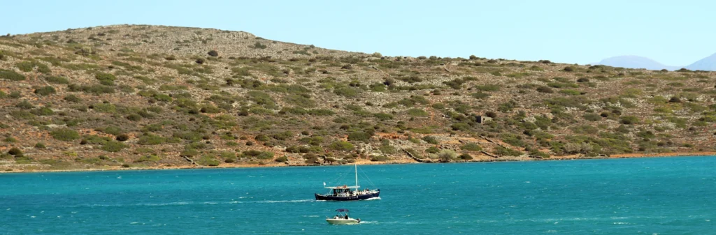 Panoramic view of Elounda Bay with a boat on turquoise water in Crete