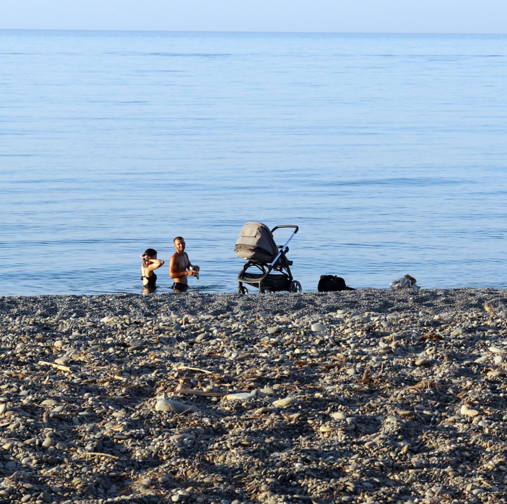 Family with stroller near calm beach sea in Crete Greece