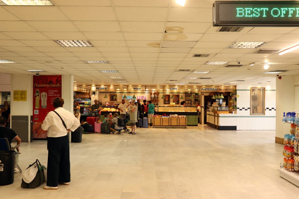Travelers waiting near cafés and food counters inside Heraklion Airport