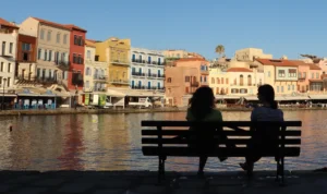 Two women sitting by the Venetian Harbour with a view of Chania Old Town